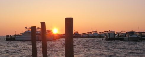 A photo of the sun rising over boats