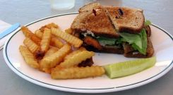 A soft shell crab sandwich with french fries and a pickle