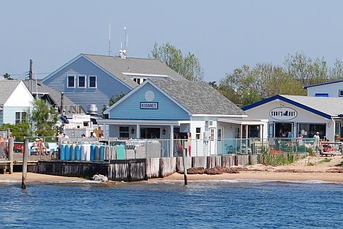 A small pier and sandy beach with several attractive buildings