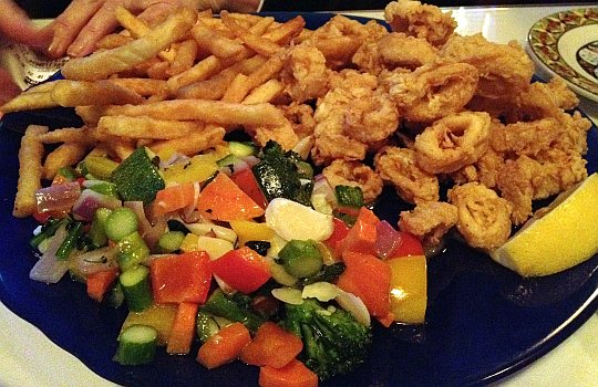 a plate of fired calamari with vegitables and fries