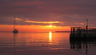 A sailboat, sunset, and pier